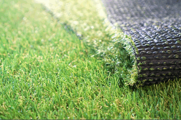 a close up of artificial turf that shows both the grass and the drainage mat underneath